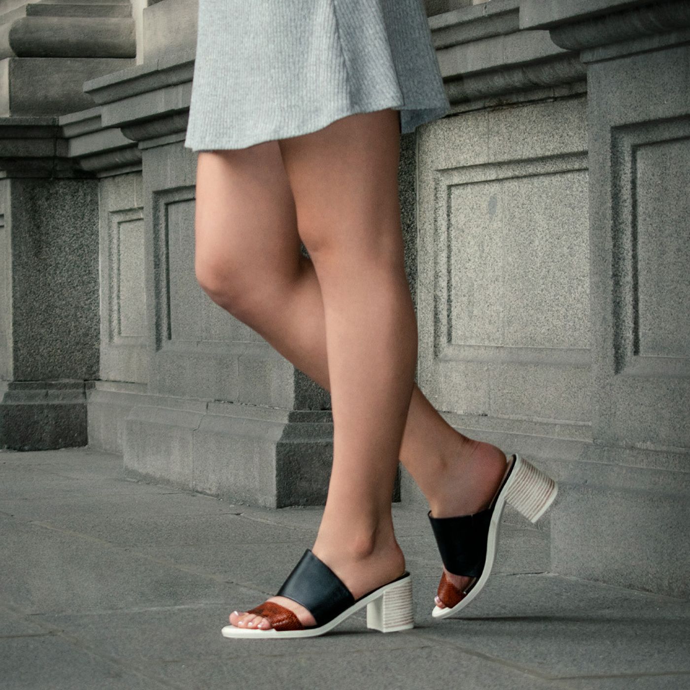 Close view of black sandals with broad light-coloured heels.