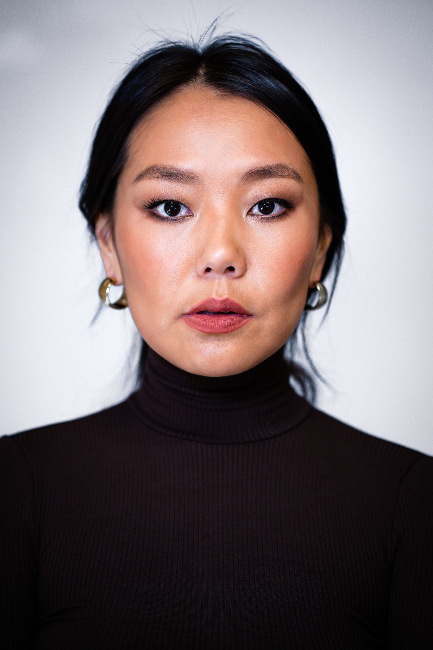 Woman wearing small hoop earrings and a high-neck black top.