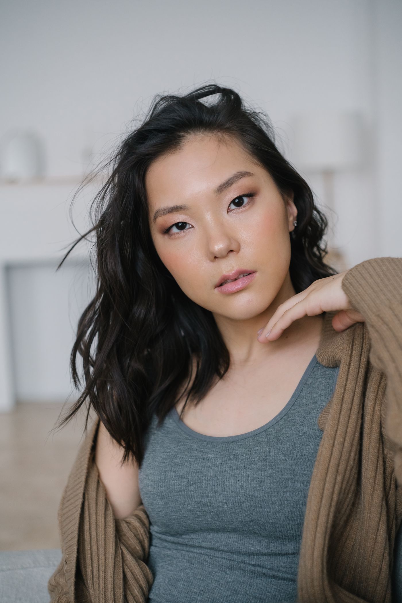 Woman in a grey sleeveless top with an open brown cardigan.