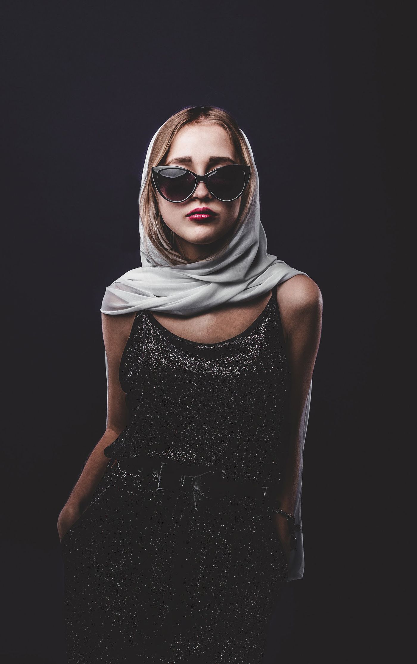 Woman wearing a lightweight pale scarf with a dark sleeveless outfit.