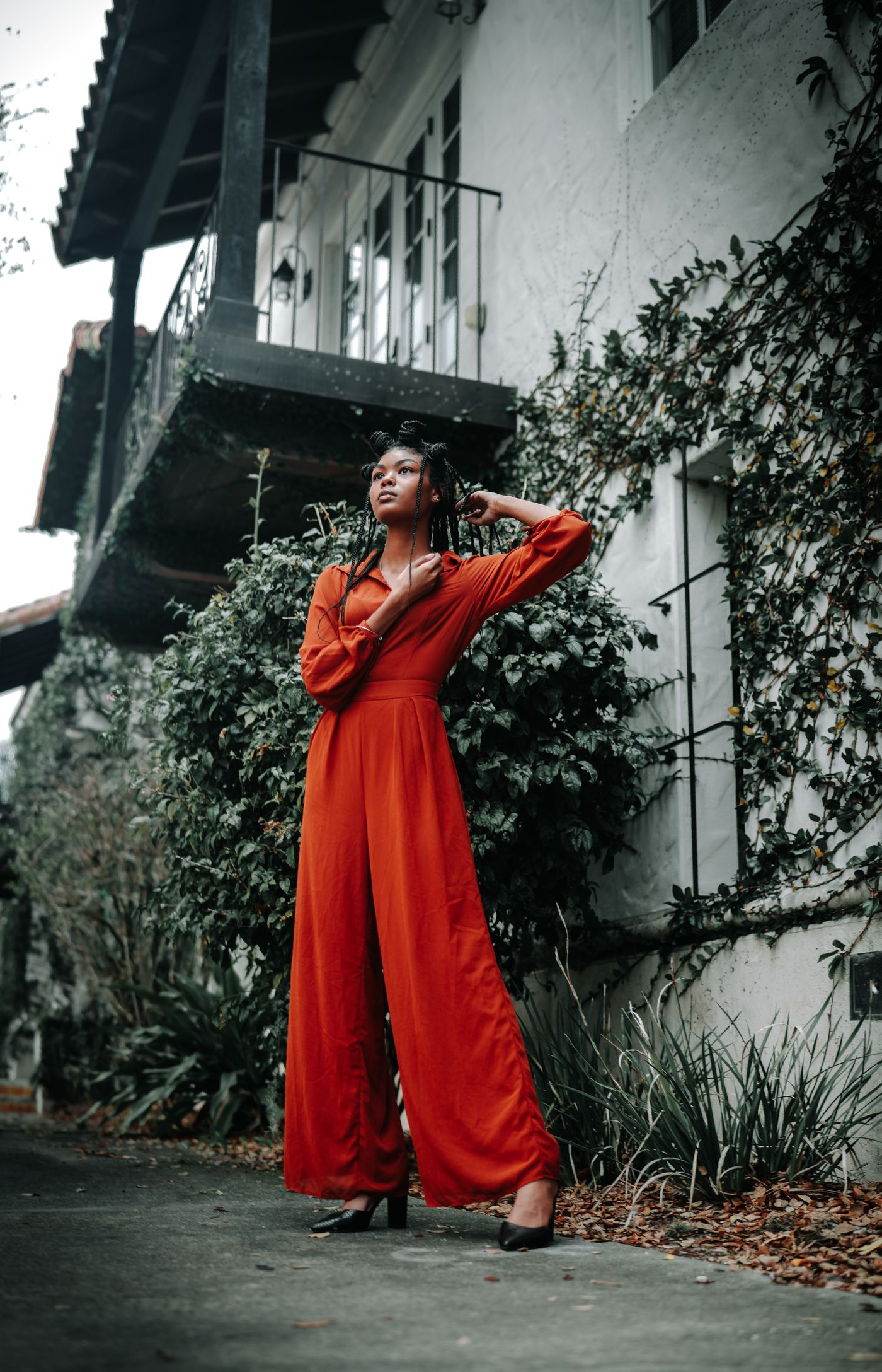 Woman wearing a rust-red wide-leg jumpsuit outdoors.
