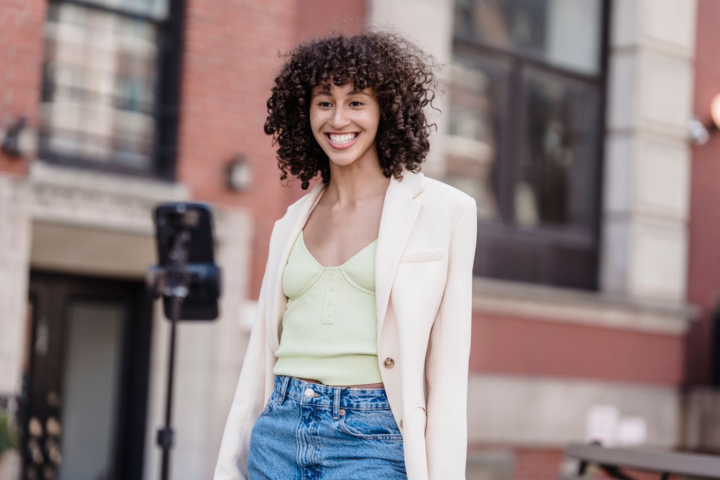 Woman wearing a pale green top under a cream blazer.