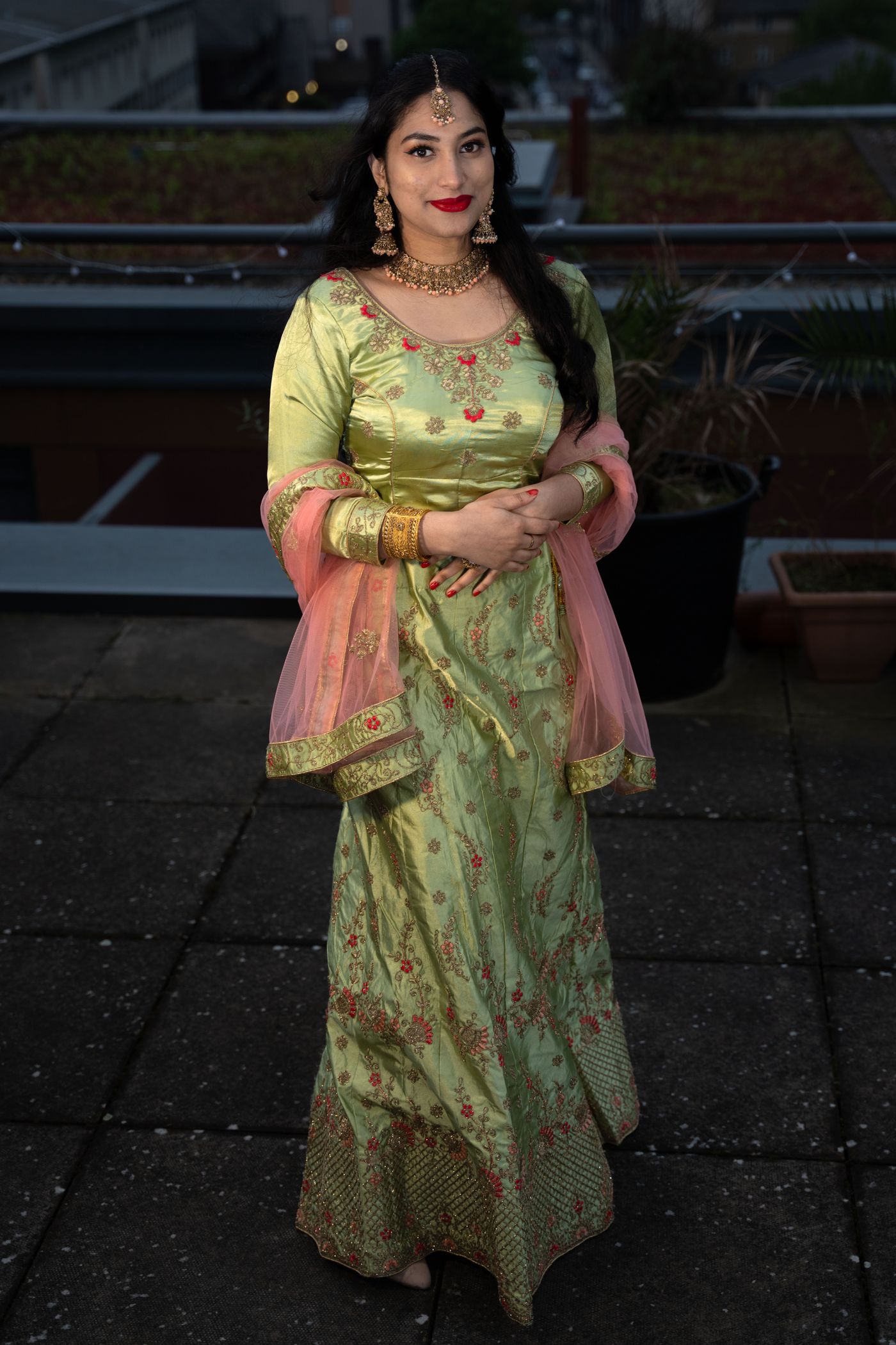 Woman wearing a green festive outfit outside after dark.