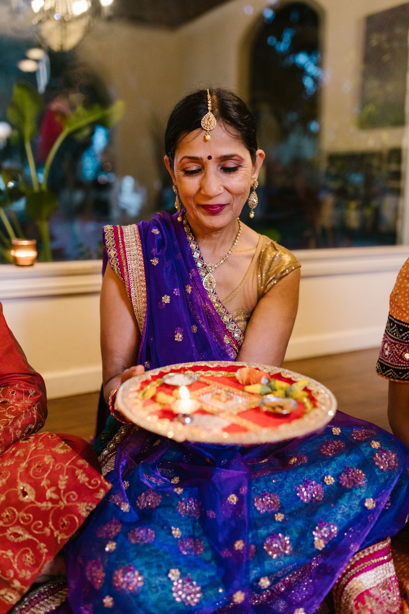 Woman wearing a blue festive lehenga while holding a tray of lamps.