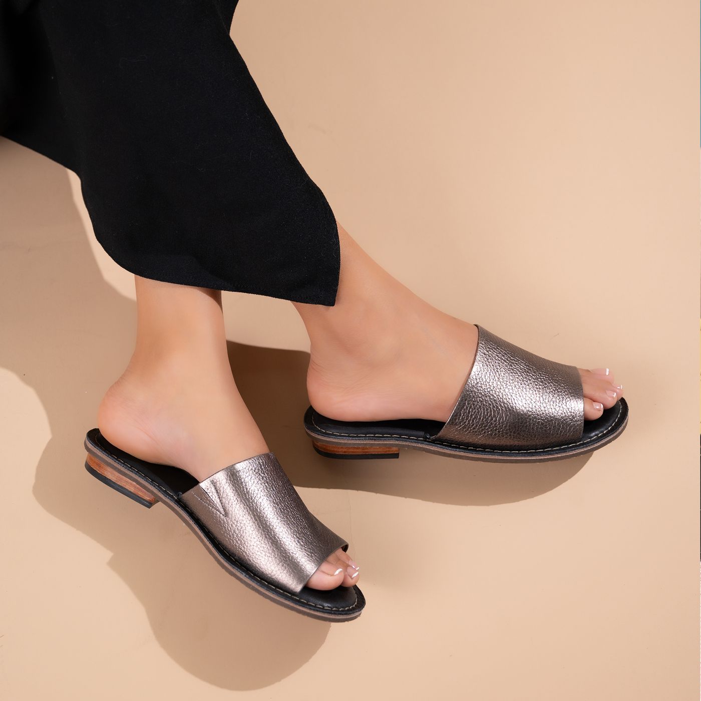Silver flat sandals worn with cropped black trousers.