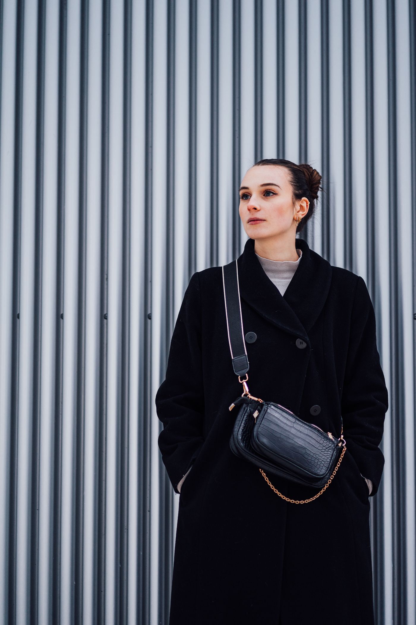 Woman wearing a small crossbody bag over a dark coat.