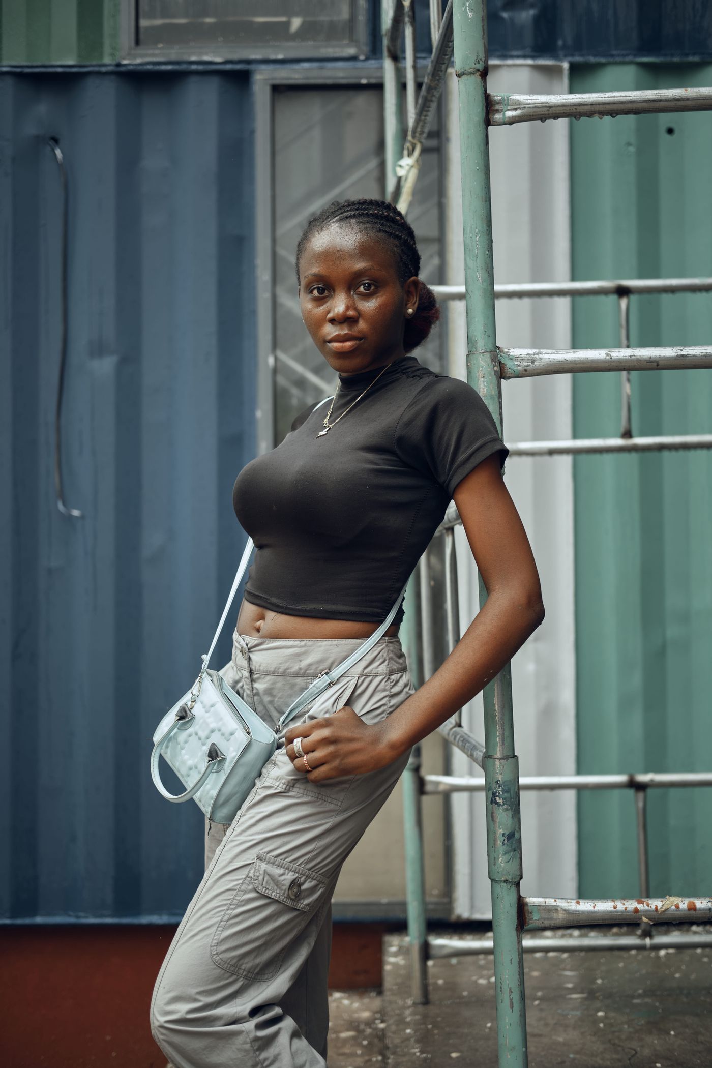 Woman wearing loose trousers and a fitted black top with a small shoulder bag.