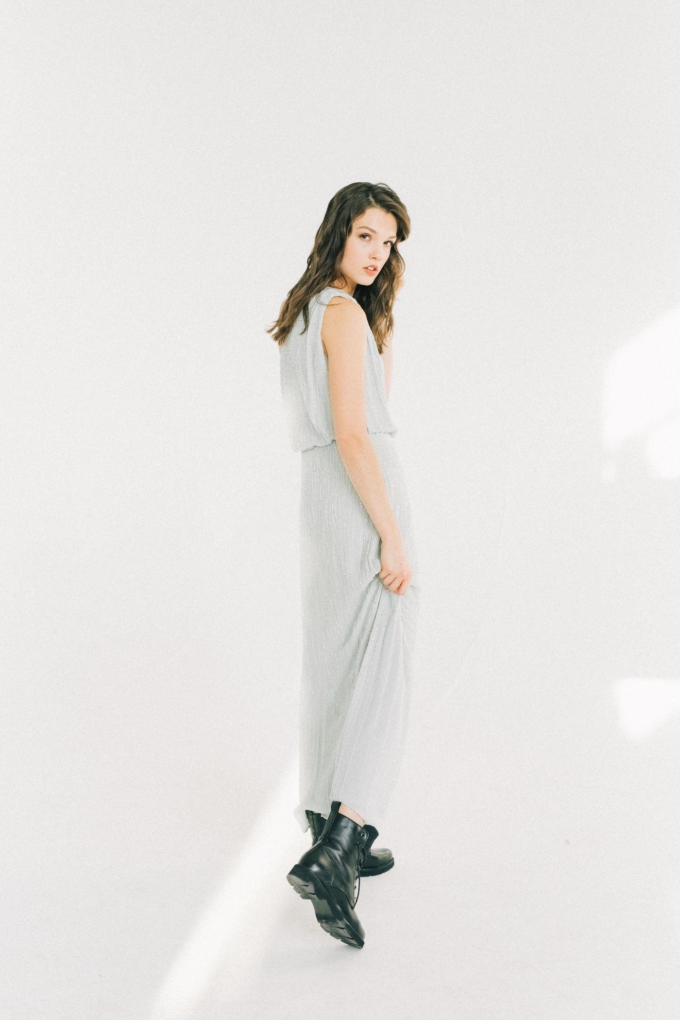 Woman wearing a long pale dress with black ankle boots.